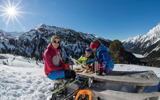 Three people are having an outdoor snack in winter; two are studying a map